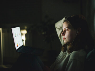 Eine Frau sitzt vor ihrem Notebook-Computer. Auf dem Monitor sind Diagramme abgebildet.